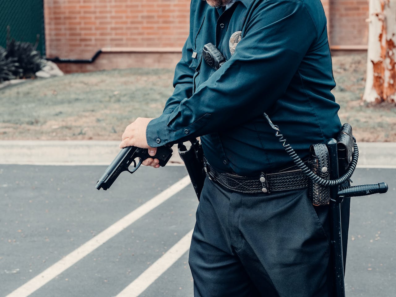 A police officer adjusting a firearm outdoors in a tactical situation, ensuring safety.
