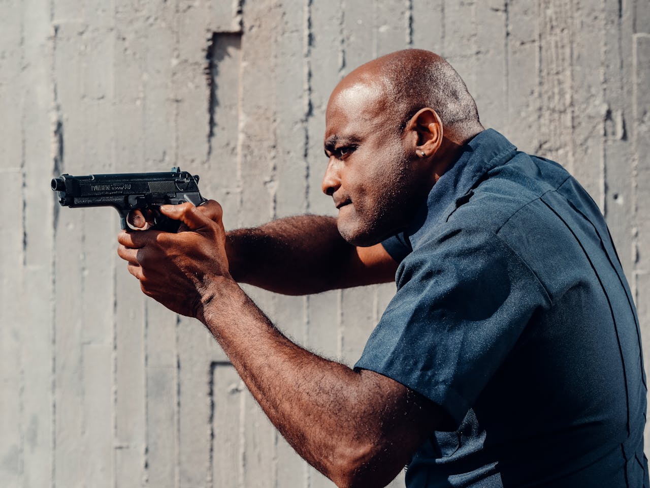 Officer in uniform aiming pistol during training. Side view, focused expression.